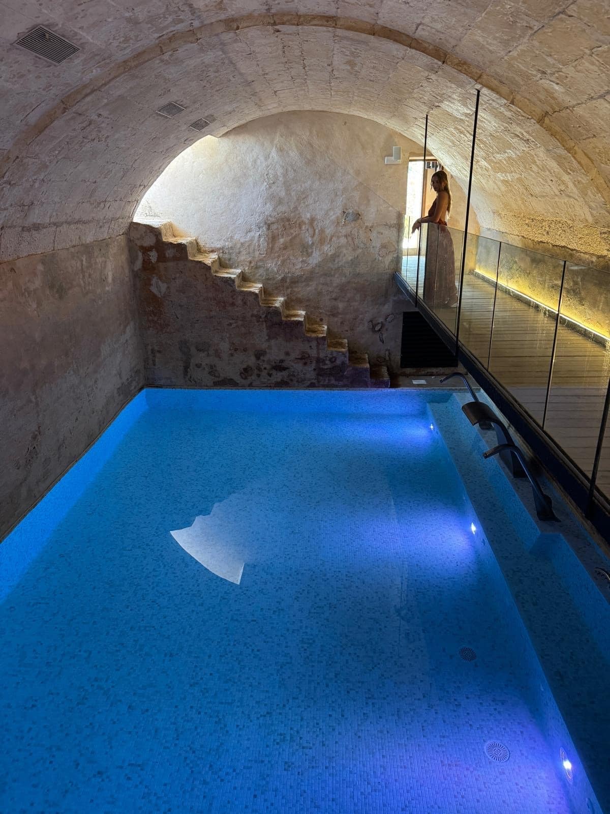 Beleuchteter Indoor-Pool unter authentischem Steingewölbe mit historischer Treppe im Spa-Bereich des Chōju Retreat Menorca