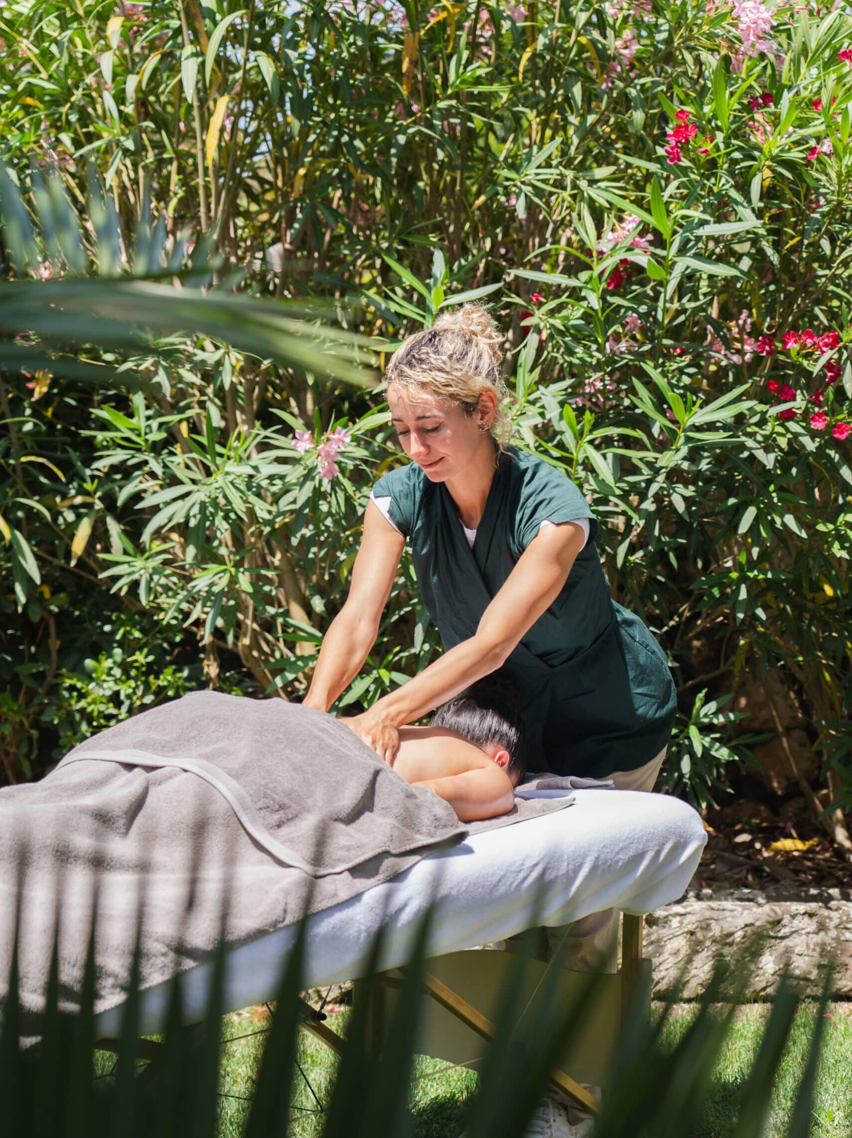 Massage-Behandlung im Freien inmitten blühender mediterraner Vegetation im Chōju Retreat Menorca