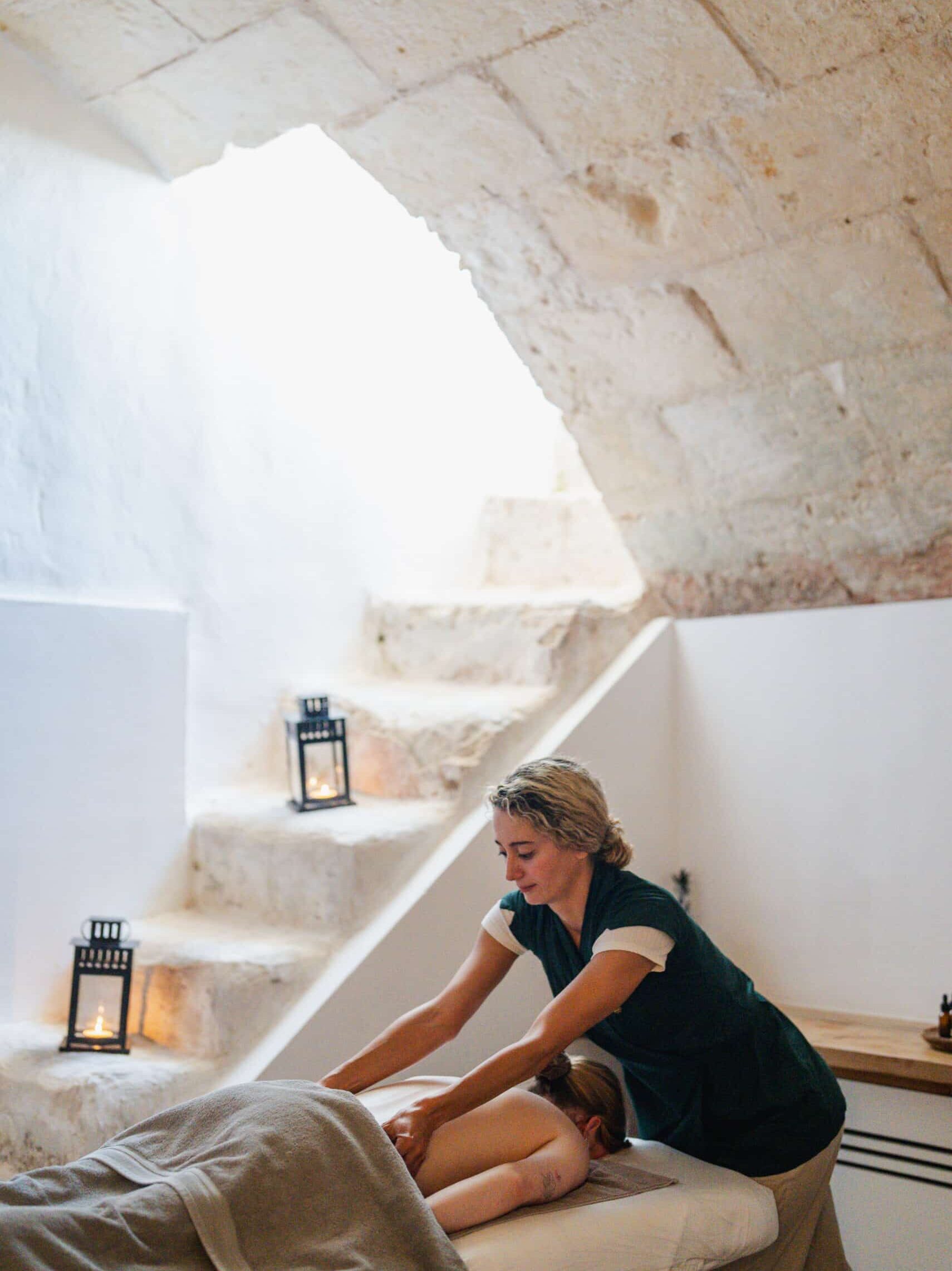 Massage-Behandlung in einer Gewölbe-Spa-Suite mit Natursteinwänden und Kerzenlicht im Chōju Retreat Menorca