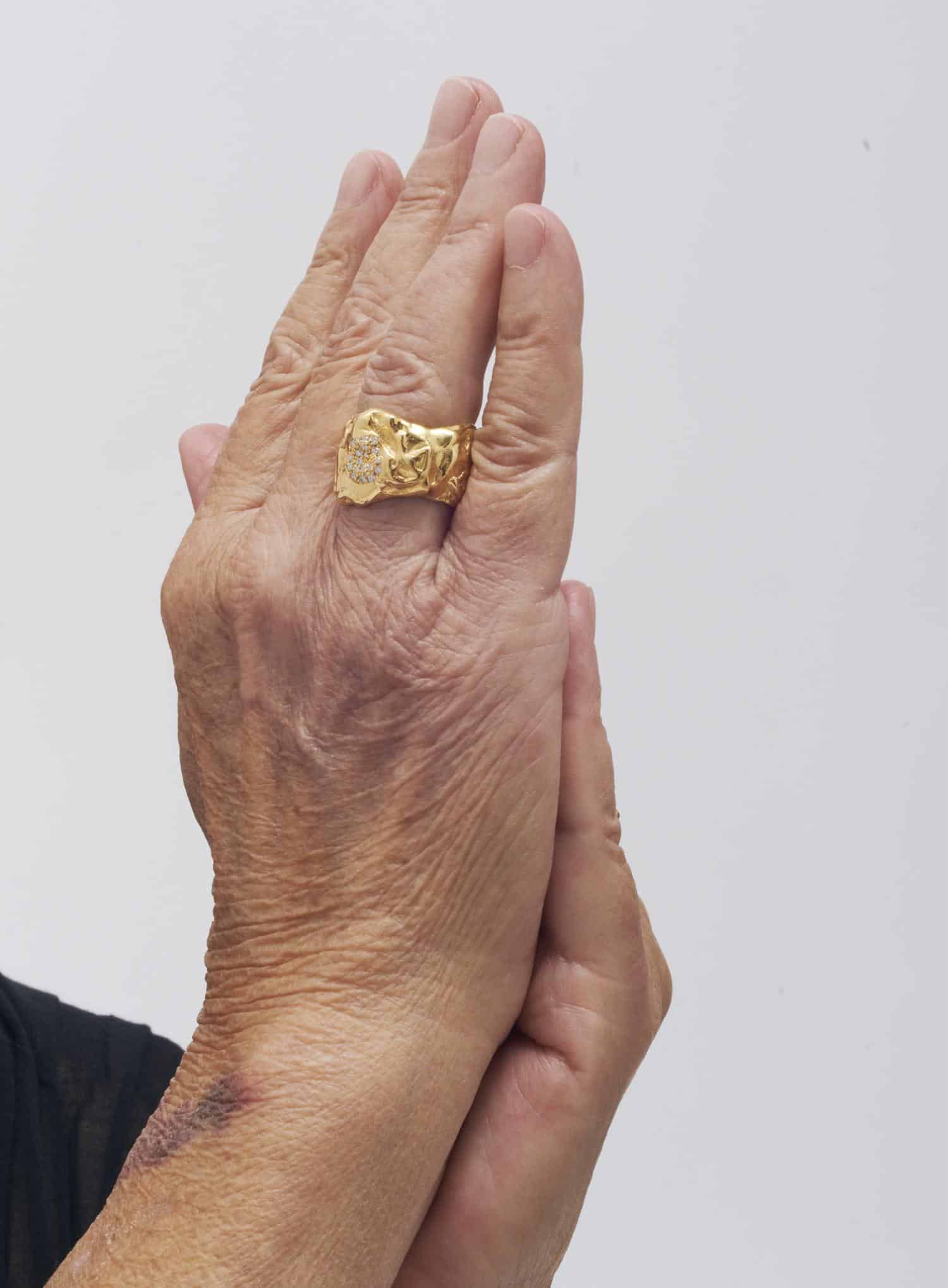 Der einzigartige Goldring von Yan Jiang – Fine Edition, geschmückt mit funkelnden Details, zieht an einer behutsam gefalteten Hand die Blicke auf sich.