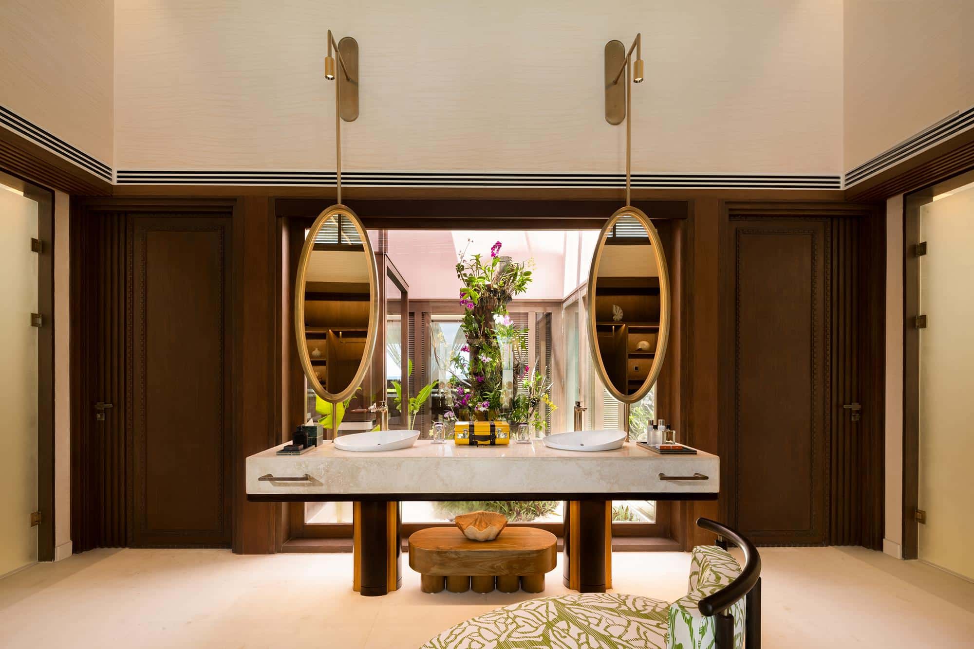 Zwei elegante Waschtische mit ovalen Spiegeln rahmen eine opulente Blumenpracht in dieser luxuriösen Villa auf den Malediven ein.