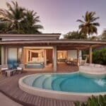 Erleben Sie einen ruhigen Abend in der Temptation Beach Pool Villa des LUX* South Ari Atoll, wo sich private Poollandschaft und elegantes Interieur unter dem rosa Abendhimmel vereinen.