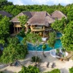 Ein atemberaubendes Hotelensemble mit Strohdachern und weitlaufigem Poolbereich fugt sich nahtlos in die grune Inselkulisse ein und definiert zukunftigen Luxus neu.