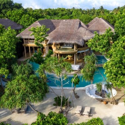 Ein atemberaubendes Hotelensemble mit Strohdachern und weitlaufigem Poolbereich fugt sich nahtlos in die grune Inselkulisse ein und definiert zukunftigen Luxus neu.